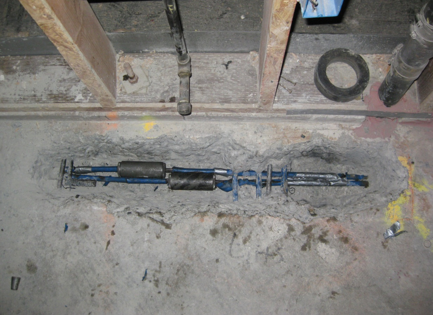 Close-up of mechanical couplers joining severed steel cables within a concrete pocket of a post tension slab.